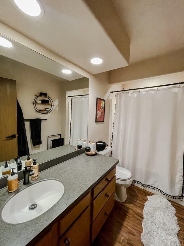 full bathroom featuring toilet, recessed lighting, wood finished floors, and vanity