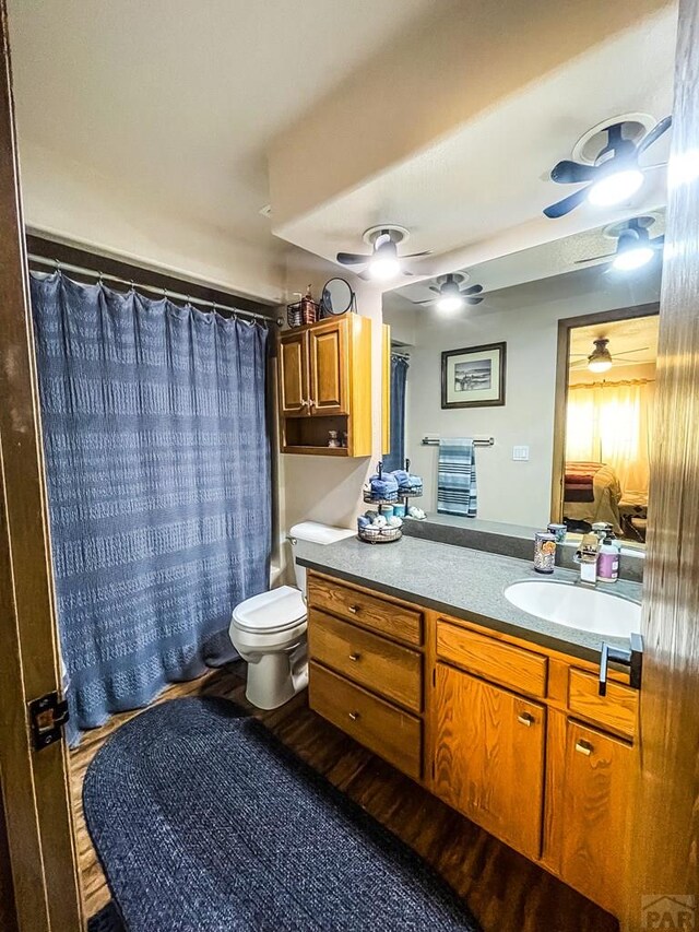 bathroom with a ceiling fan, vanity, toilet, and wood finished floors