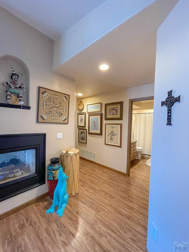 corridor featuring recessed lighting, visible vents, baseboards, and wood finished floors