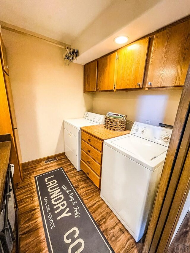 laundry area with washing machine and dryer, dark wood-style flooring, visible vents, baseboards, and cabinet space