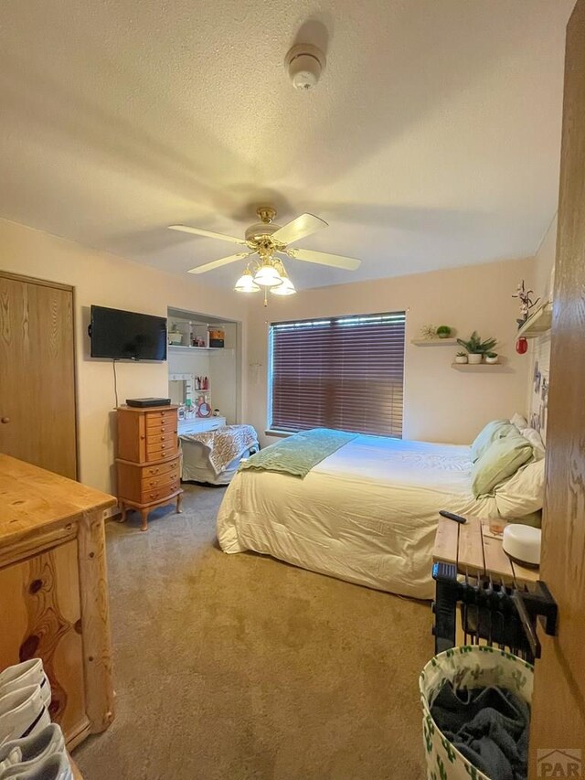 carpeted bedroom with a textured ceiling and ceiling fan