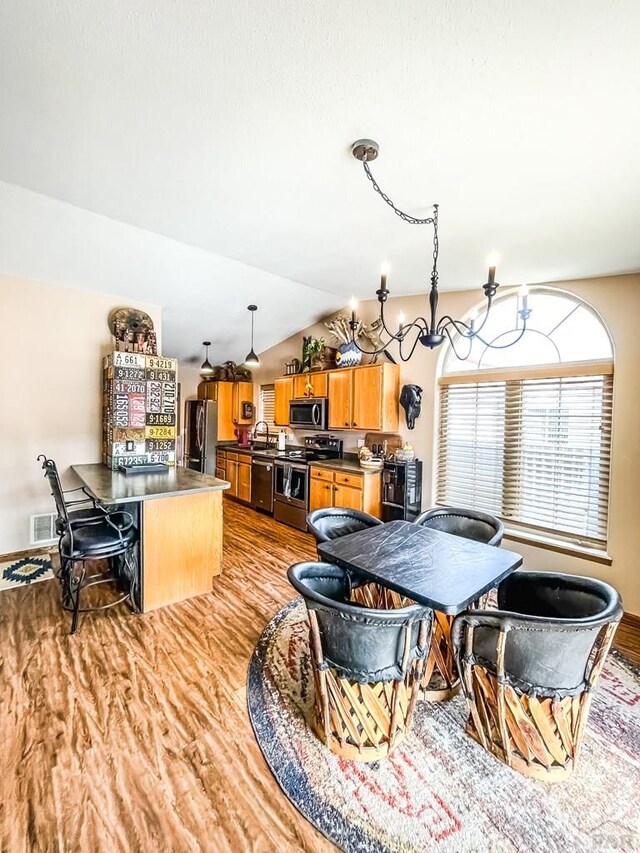 dining area featuring visible vents, an inviting chandelier, vaulted ceiling, light wood-type flooring, and baseboards