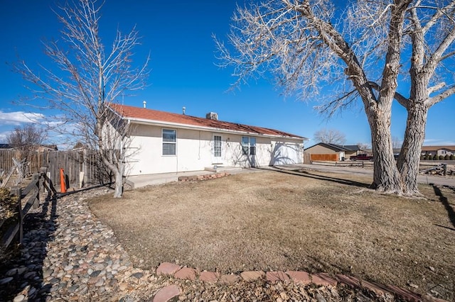 back of property featuring fence, a lawn, and stucco siding