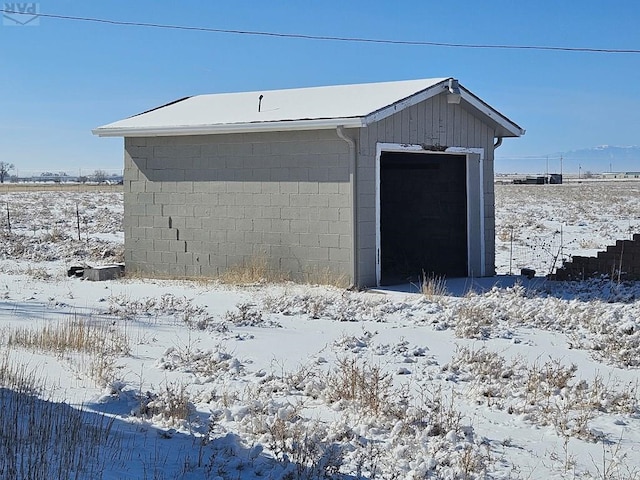 snow covered structure with an outbuilding