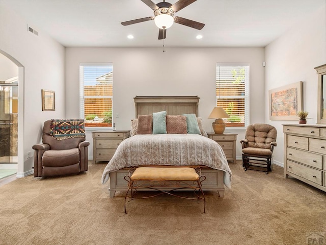 bedroom with arched walkways, light carpet, visible vents, and baseboards