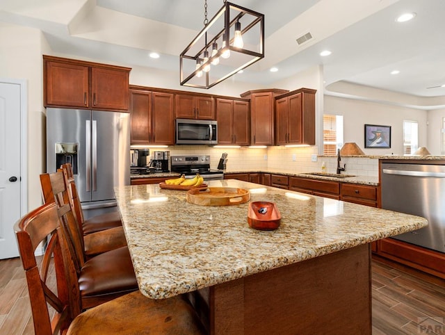 kitchen with stainless steel appliances, a tray ceiling, wood tiled floor, and tasteful backsplash