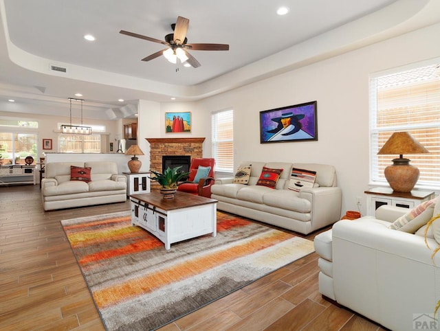 living area with visible vents, a raised ceiling, wood tiled floor, a fireplace, and recessed lighting