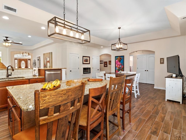 dining area with visible vents, arched walkways, a raised ceiling, wood tiled floor, and recessed lighting