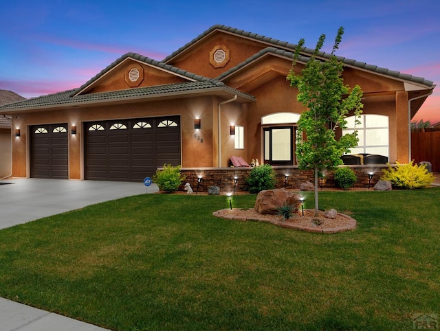 view of front of property with stucco siding, a lawn, a garage, driveway, and a tiled roof