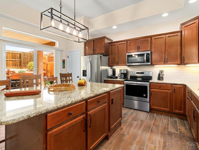 kitchen with decorative backsplash, appliances with stainless steel finishes, a center island, wood tiled floor, and recessed lighting