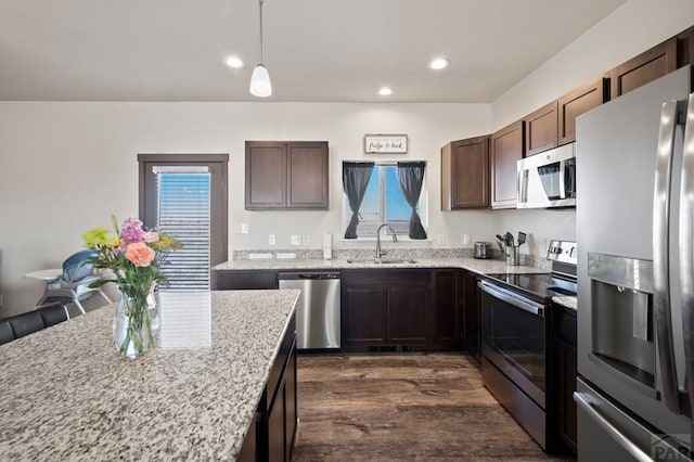 kitchen with stainless steel appliances, recessed lighting, a sink, dark brown cabinets, and light stone countertops