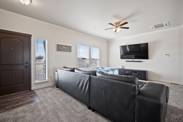 carpeted living room featuring a ceiling fan, visible vents, crown molding, and baseboards