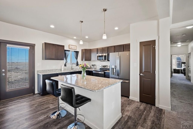 kitchen with dark brown cabinetry, stainless steel appliances, a sink, a center island, and decorative light fixtures