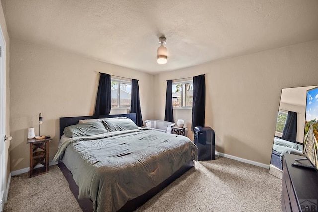 bedroom with multiple windows, baseboards, carpet flooring, and a textured ceiling