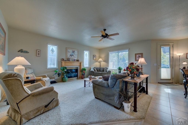 living room featuring a fireplace with flush hearth, baseboards, a ceiling fan, and tile patterned flooring