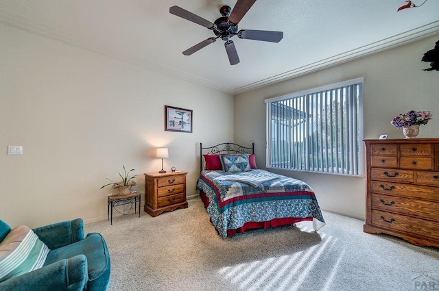 carpeted bedroom featuring crown molding, baseboards, and a ceiling fan