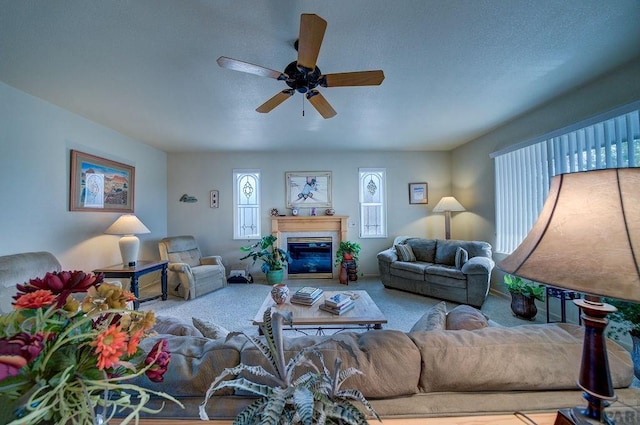 carpeted living area with a glass covered fireplace and a ceiling fan