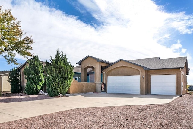 view of front facade with an attached garage, driveway, and stucco siding