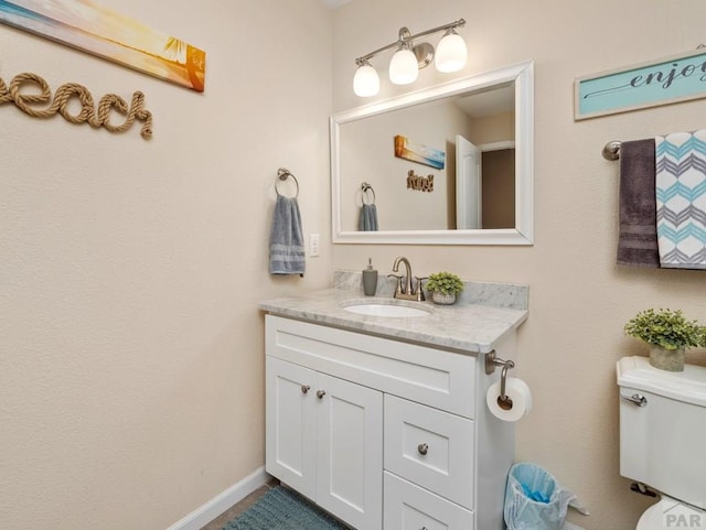 bathroom with vanity, toilet, and baseboards