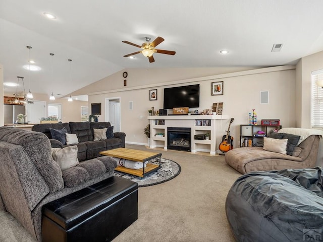 living area featuring carpet floors, lofted ceiling, visible vents, and a glass covered fireplace