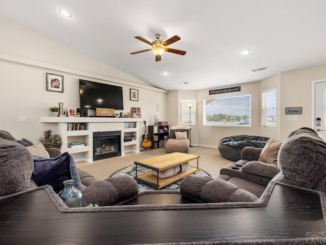 living area with lofted ceiling, visible vents, a ceiling fan, a glass covered fireplace, and light carpet