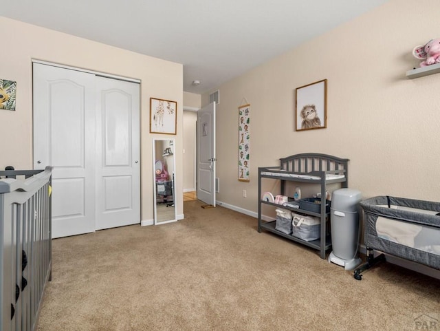 bedroom with a closet, light carpet, and baseboards