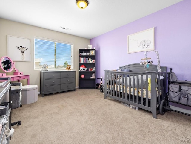 bedroom featuring a nursery area, light colored carpet, and visible vents