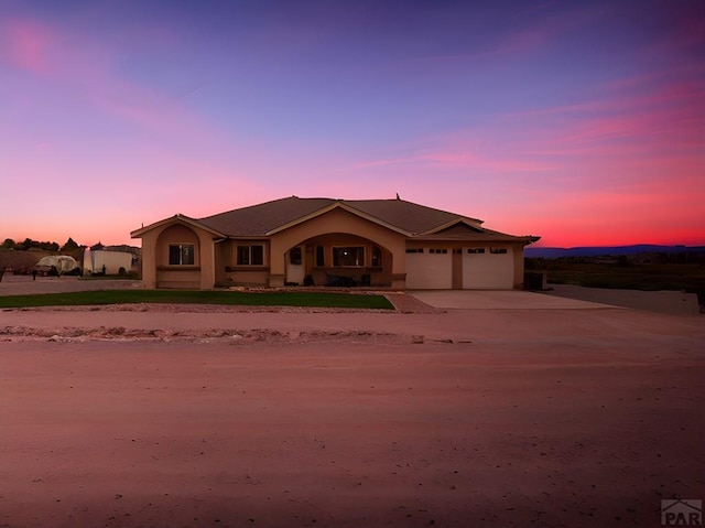 view of front of house with a garage, driveway, and stucco siding