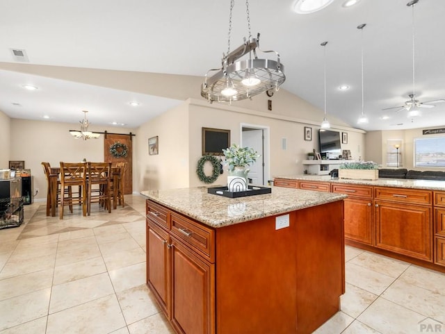 kitchen with light tile patterned floors, a kitchen island, open floor plan, light stone countertops, and decorative light fixtures