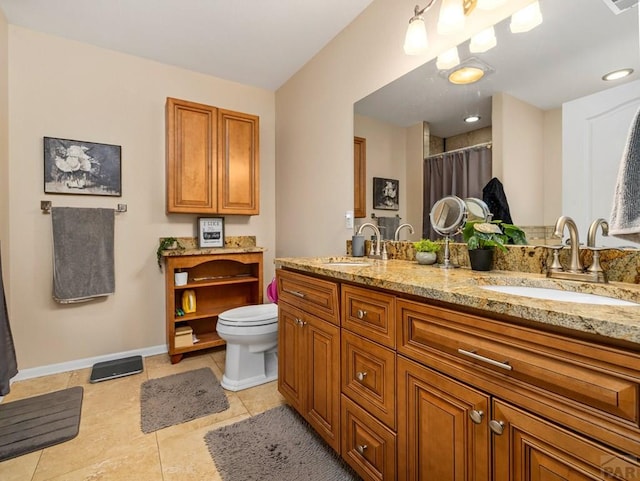 bathroom featuring double vanity, tile patterned flooring, a sink, and baseboards