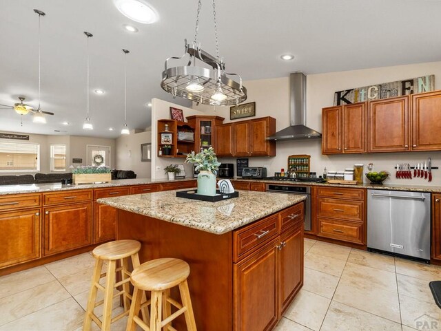 kitchen with light tile patterned floors, a kitchen breakfast bar, appliances with stainless steel finishes, a center island, and wall chimney exhaust hood