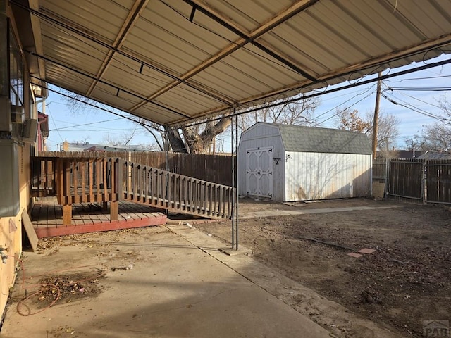 view of patio featuring a deck, a shed, an outdoor structure, and a fenced backyard