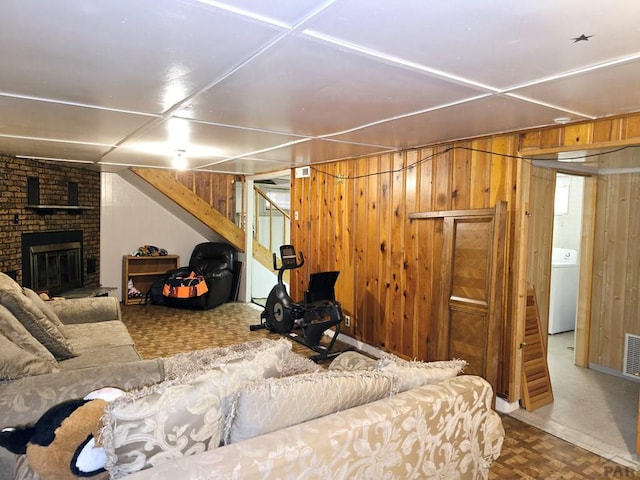 living area with washer / clothes dryer, visible vents, and wood walls