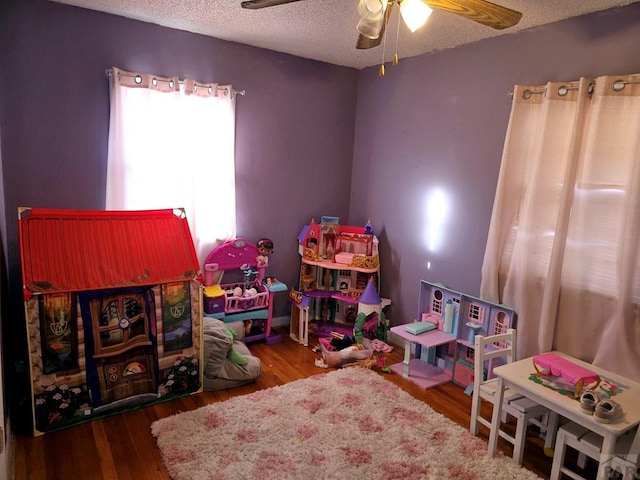 game room with a ceiling fan, a textured ceiling, and wood finished floors