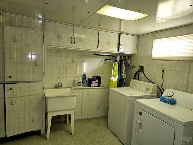 laundry room featuring cabinet space, tile walls, and washing machine and clothes dryer