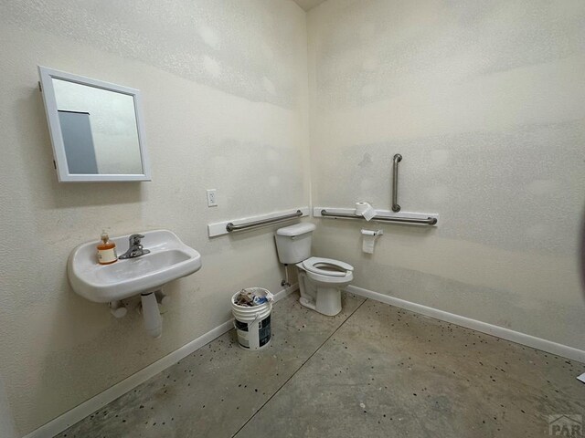 bathroom featuring concrete flooring, a sink, toilet, and baseboards