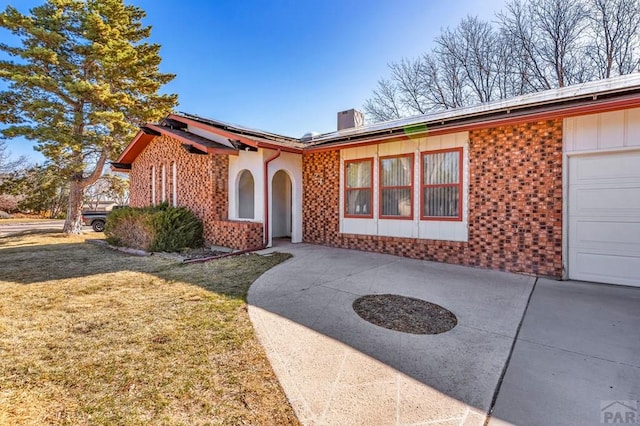 view of front of home with brick siding, solar panels, concrete driveway, and a front yard