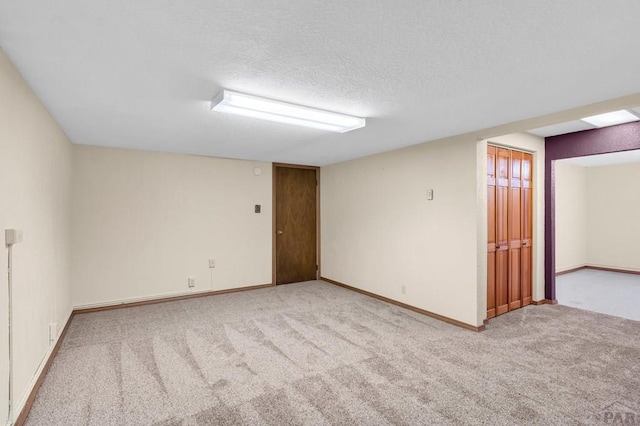 carpeted empty room with baseboards and a textured ceiling