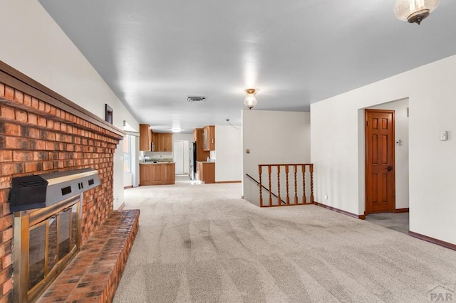 living area with light carpet, visible vents, a fireplace, and baseboards