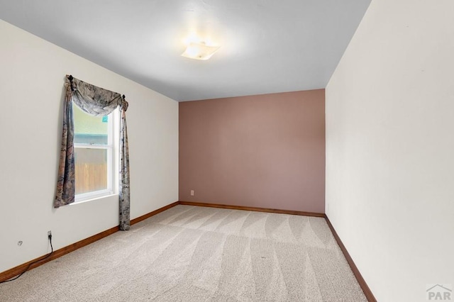 empty room featuring light carpet and baseboards