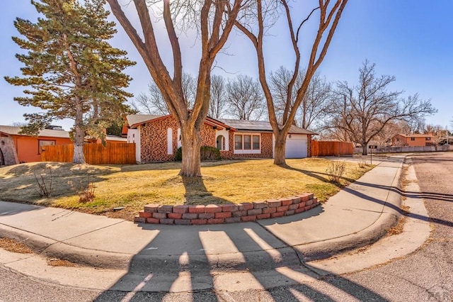 view of front of property with brick siding, fence, roof mounted solar panels, driveway, and an attached garage