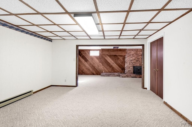 interior space featuring wooden walls, baseboards, a baseboard heating unit, and carpet