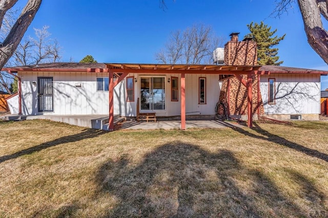 back of property featuring a patio area, a lawn, and a chimney