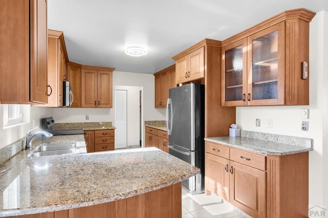 kitchen featuring light stone counters, appliances with stainless steel finishes, a peninsula, and a sink