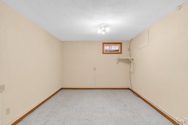 below grade area with light floors, a textured ceiling, and baseboards