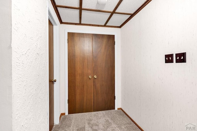 hall featuring carpet flooring and a textured wall