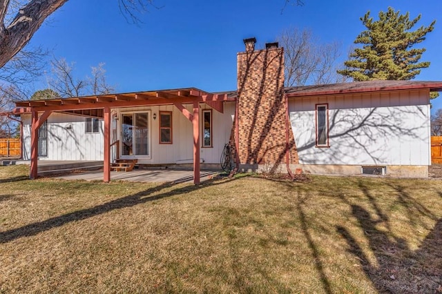 rear view of house with a yard, a patio area, fence, and a chimney