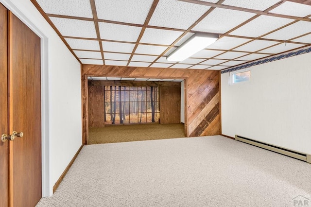 hall with a baseboard radiator, baseboards, wooden walls, and carpet flooring