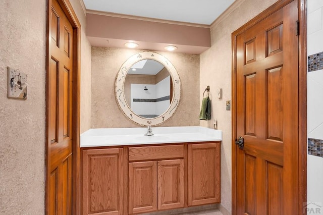 bathroom featuring vanity, a textured wall, and ornamental molding