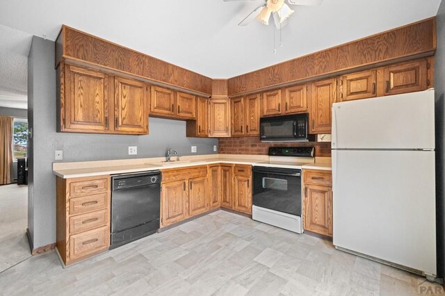 kitchen with brown cabinets, black appliances, light countertops, and a sink